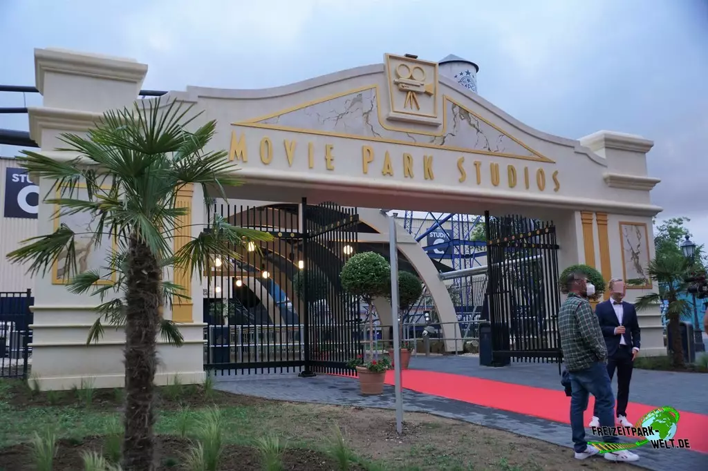 Movie Park Studio Tour im Movie Park Germany - 2021: Direkt über die Köpfe der wartenden Besucher und dem imposante Studio Tor führt die Strecke der neuen Achterbahn.